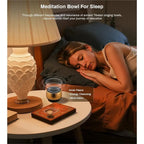 Woman lying in bed with a BowLunex Singing Bowl Machine surrounded by a warm and cozy bedroom setting.