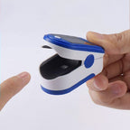 Finger pulse oximeter being held with a finger on a white background