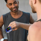 Man using a OxiLuny v2 Pulse Oximeter on his finger with a blurred background