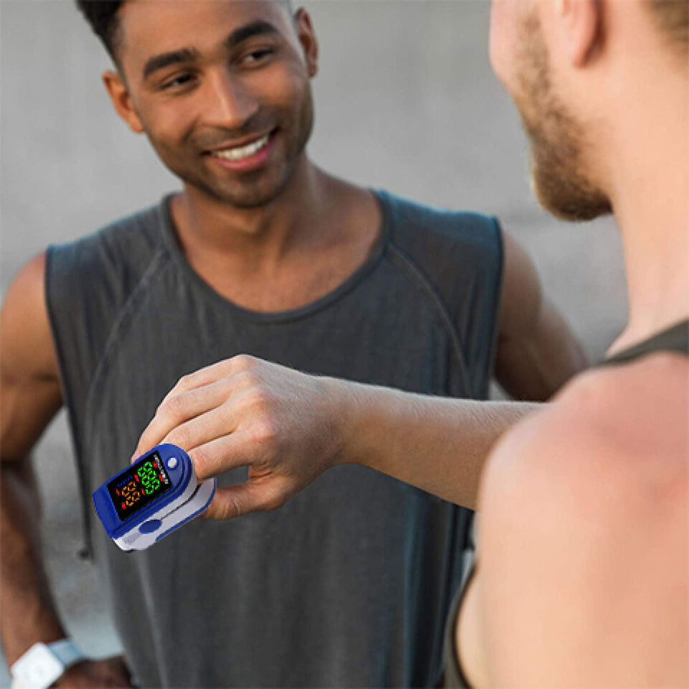 Man using a OxiLuny v2 Pulse Oximeter on his finger with a blurred background