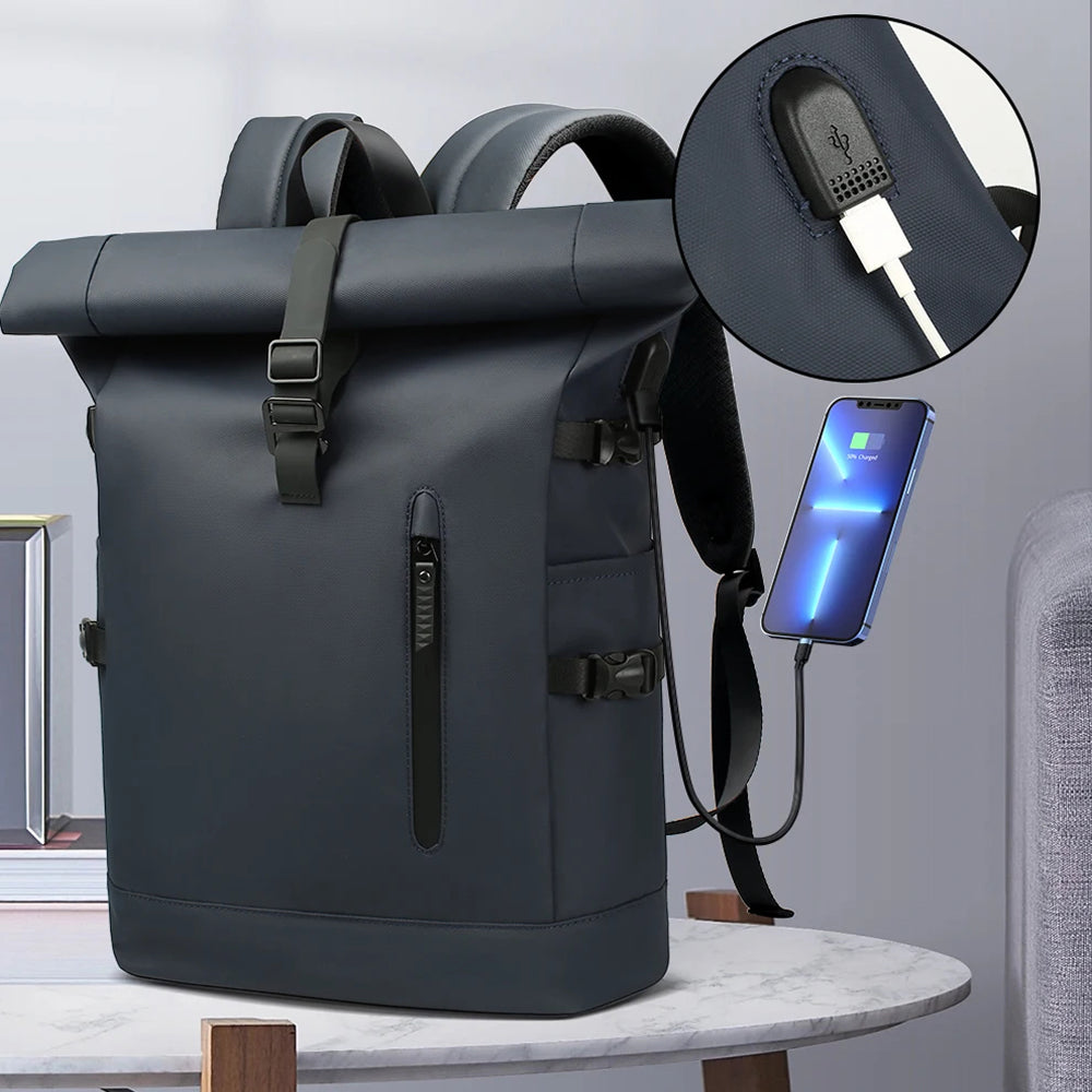 A dark gray  SafeiPack Ultimate Anti-Theft Backpack with a roll-top closure, shown on a marble table with a phone plugged into its side charging port. An inset circle highlights the USB charging port detail.