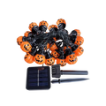 Solar-powered Sunpikoex Solar Pumpkin Lights featuring orange pumpkin-shaped bulbs with black jack-o'-lantern faces, connected by a black wire with a small solar panel and black ground stakes on a white background.