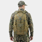 A man wearing a camouflage hunting jacket, pants, and cap, viewed from behind while wearing a tan The Trekorago Hunting Backpack with MOLLE webbing and compression straps, against a light gray background.